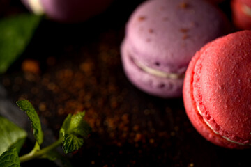 Colored macaroons. Delicious sweet colorful French desserts on black background