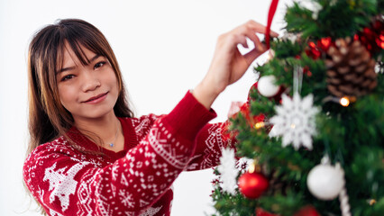 Merry christmas and happy holidays, an asian woman is decorating spruce tree