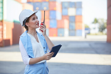 businesswoman talking with wireless radio in containers warehouse storage