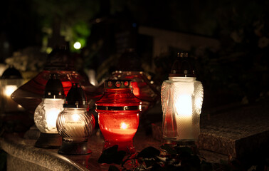 red and white candles in the cemetery at night
