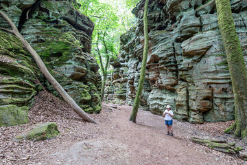 Hiking trail between huge rock formation, female hiker checking her cell phone in Teufelsschlucht...