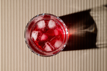 Red drink with ice in whisky glass