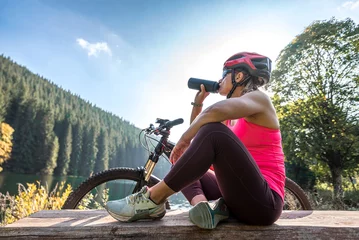  Young woman cyclist  have a rest on cycle trail near forest lake. © Sabrewolf