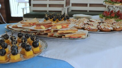 Beautifully decorated catering banquet table with canapes appetizers. Served table with food. Lots of snacks on the holiday table. buffet food set for corporate day celebration.