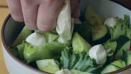 Healthy organic food. The cook prepares a salad with cucumber and radish, the cook prepares a light salad, vegetarian food, a handsome caucasian male cook presents a delicious dish, close-up.