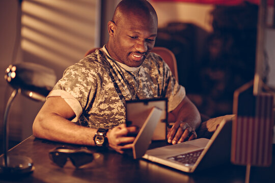 Smiling soldier looking at picture frame at base