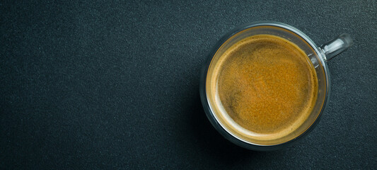 Glass Cup of Espresso coffee. Top view, on a black background, free copy space. Natural coffee.