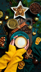 Christmas concept. Cup of fragrant cappuccino coffee in female hands. New Year's decor. On a dark background.