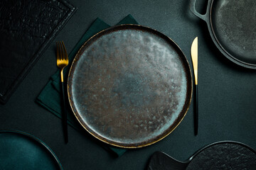 Gold knives and forks on a black background, empty black plate. Beautiful gold cutlery. View from...