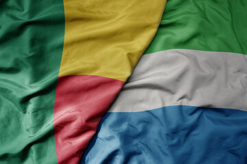 Fototapeta premium big waving national colorful flag of benin and national flag of sierra leone .