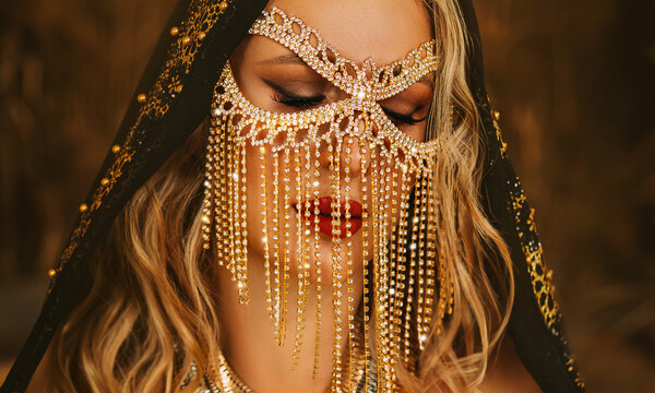 Art portrait fantasy sexy arabic woman in black shawl abaya hood. clothes gold accessories gold chain veil mask burqa hide beauty face. Oriental fashion model girl Bedouin queen. summer desert Egypt