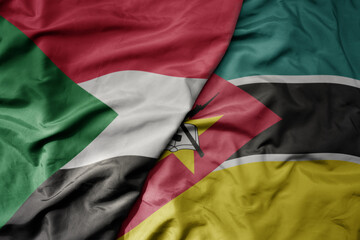 big waving national colorful flag of sudan and national flag of mozambique .