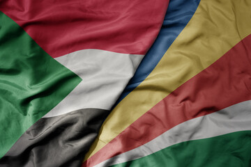 big waving national colorful flag of sudan and national flag of seychelles .