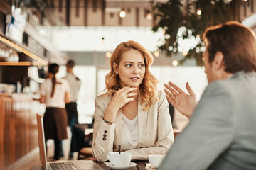Young businesswoman talking to colleague in cafe