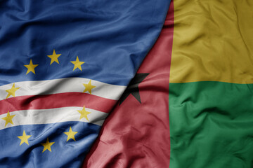 big waving national colorful flag of cape verde and national flag of guinea bissau .