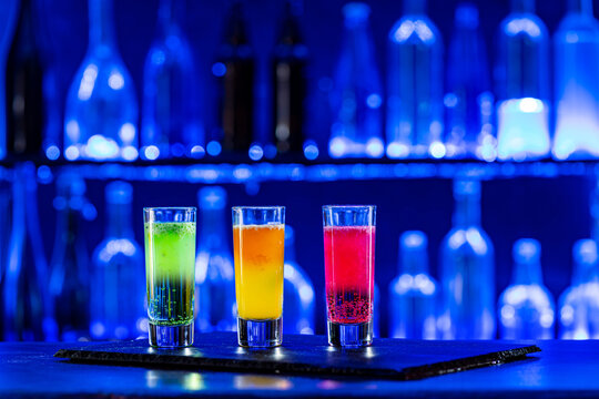Cocktails Party Shots and Shooters on bar counter in a restaurant, pub. Miniature mixed drinks. Alcoholic cooler beverage at nightclub on dark background
