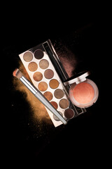 Explosion of shimmer, bronzer, highlighter powder dust, eye shadow, blush brushes on black...