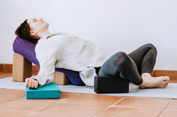 Woman doing restorative yoga supported butterfly pose with props
