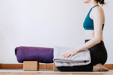 Woman preparing to do restorative yoga child's pose with props