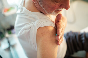 Elderly Man Applying Gel to Shoulder Pain in Bathroom, Self-Treatment, Healthcare at Home
