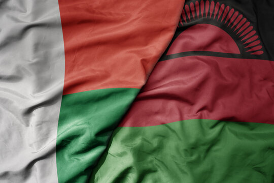 big waving national colorful flag of madagascar and national flag of malawi .