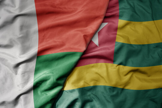 big waving national colorful flag of madagascar and national flag of togo .