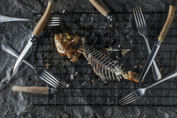 Bones left after eating grilled Dorado on dark textured background. Healthy eating concept. Seafood...