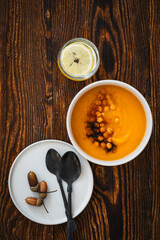 Autumn pumpkin soup on rustic wooden background, healthy vegan dinner