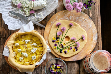 pie decorated with blooming chives and violets. Top view, wooden background.