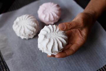 White and pink marshmallows on the paper with arm