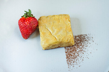 A piece of white chocolate brownie, strawberry and cinnamon.