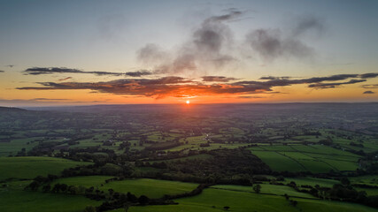 view of the sunrise above the lush green Wye Valley in South Wales shot from the trig point of the Skirrid Fawr in Abergavenny