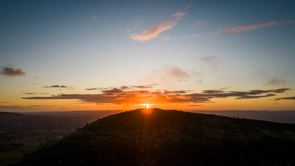 The sun rises over the Skirrid Fawr mountain near Abergavenny in the Brecon Beacons Black Mountains national park. morning walkers enjoy rugged natural beauty in Bannau Brycheiniog South Wales