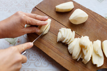 Fototapeta na wymiar Cutting peeled potatoes on the cutting board, close