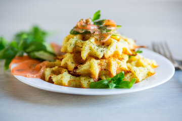 Cooked potato waffles with lightly salted red fish and herbs in a plate.
