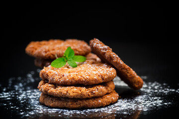 cooked sweet oatmeal cookies on black background