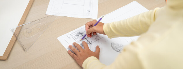 Cropped image of skilled architect designer hand draws blueprint with architectural equipment and...