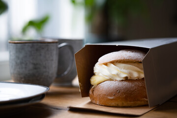 Coffee break with fresh traditional Swedish pastry, known as semla, that is still in the box from...