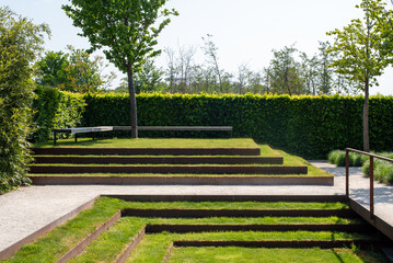 Seating for relaxing in a landscaped park. Minimalist landscape design with green grass steps