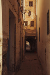 The narrow street with the lamp and small windows at old town (Medina) of Kairouan, Tunisia, in the...