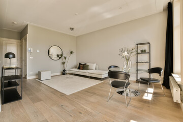 a living room with white walls and wood flooring in the center of the room is a large round mirror on the wall