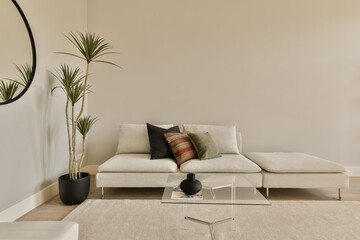 a living room with a couch, coffee table and two planters on the floor in front of the sofa