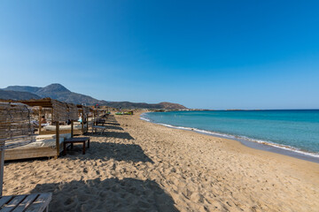 Sunbeds, deckchairs and gazebos for relaxation. View of the sea in the Island with sandy beach, cloudless and clear water. Tropical colours, peace and tranquillity. Falasarna beach, Crete, Greece.