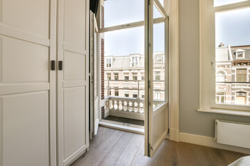 a room with wooden floors and white walls, there is an open door that leads out to the balcony area