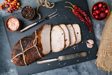 Smoked and boiled pork belly with rosemary on a black stone board. View from above.