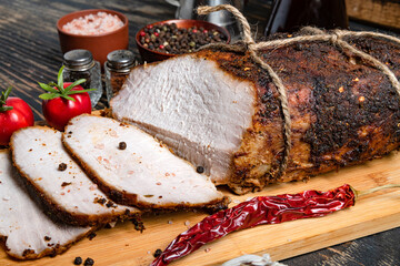 Sliced Smoked and boiled pork belly with rosemary on a wooden table. With peppers and cherry tomatoes.