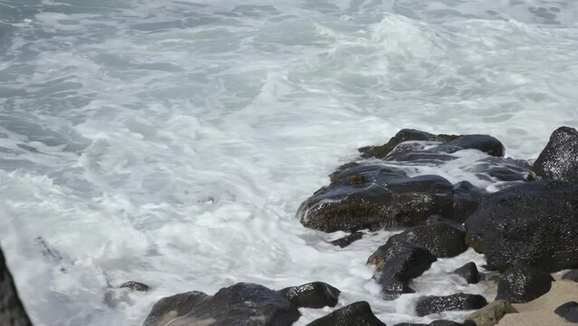 Water crashes up on to beach lava rocks maui hawaii