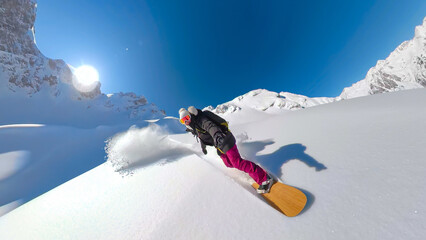 SELFIE, LENS FLARE: Happy female snowboarder enjoys riding untracked powder snow