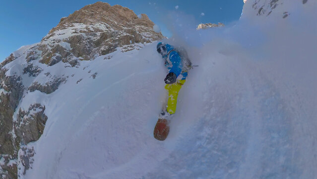 SELFIE: Extreme snowboarder riding fresh powder snow from steep snowy mountain