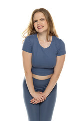 Fototapeta premium Young blond woman in sportswear pressing her crotch lower abdomen with her hands. Medical or gynecological problems, healthcare concept.